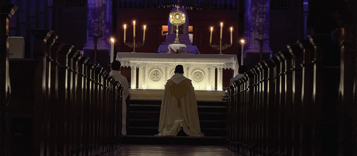 Image of priest kneeling before the blessed sacrament during adoration.