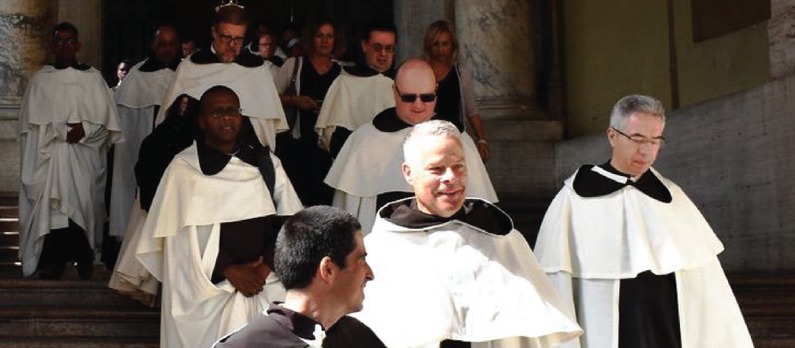 Group of Carmelites in their habits walking down steps of a building.